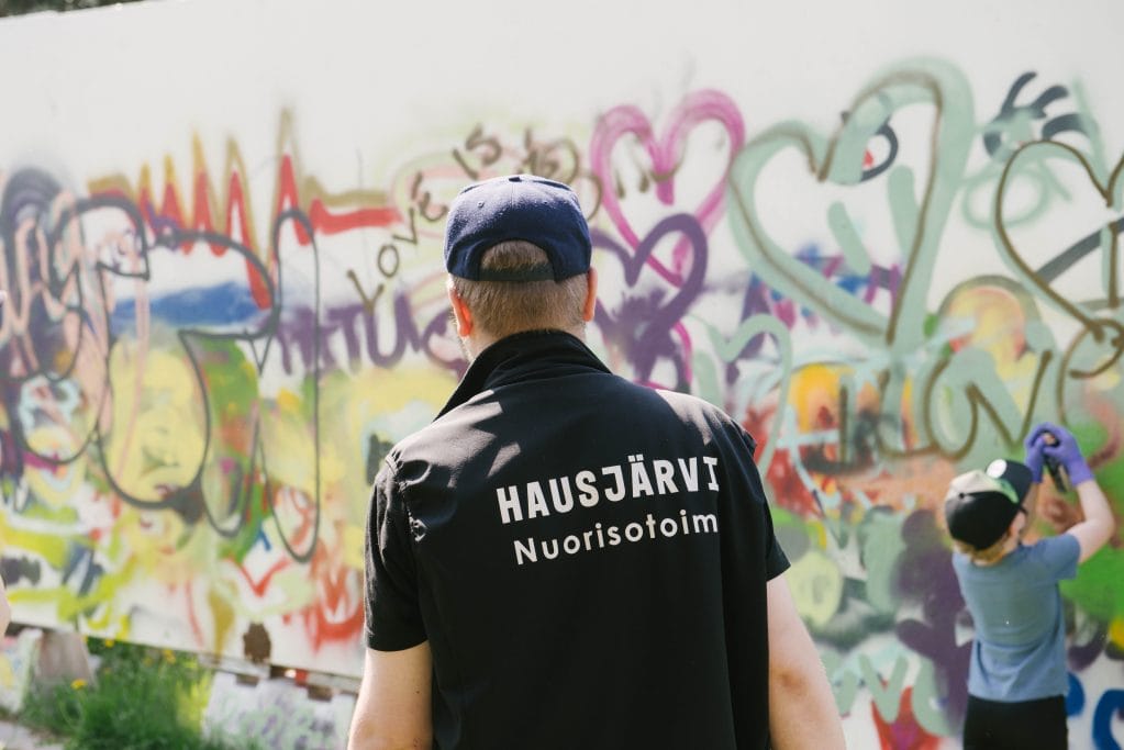 Nuorisotoimen työntekijä graffitiseinän edessä
